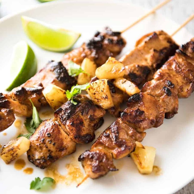Pineapple Coconut Hawaiian Chicken Skewers on a white plate garnished with caramelised pineapple pieces.