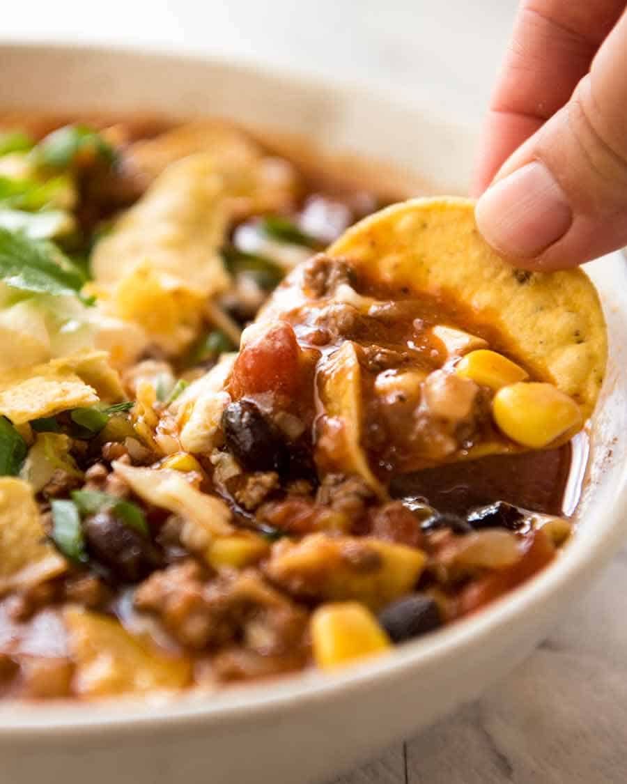 Close up of corn chip being dunked into Taco Soup