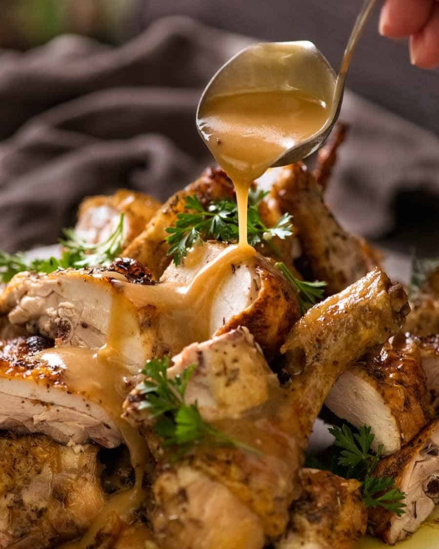 Pouring gravy over roast chicken