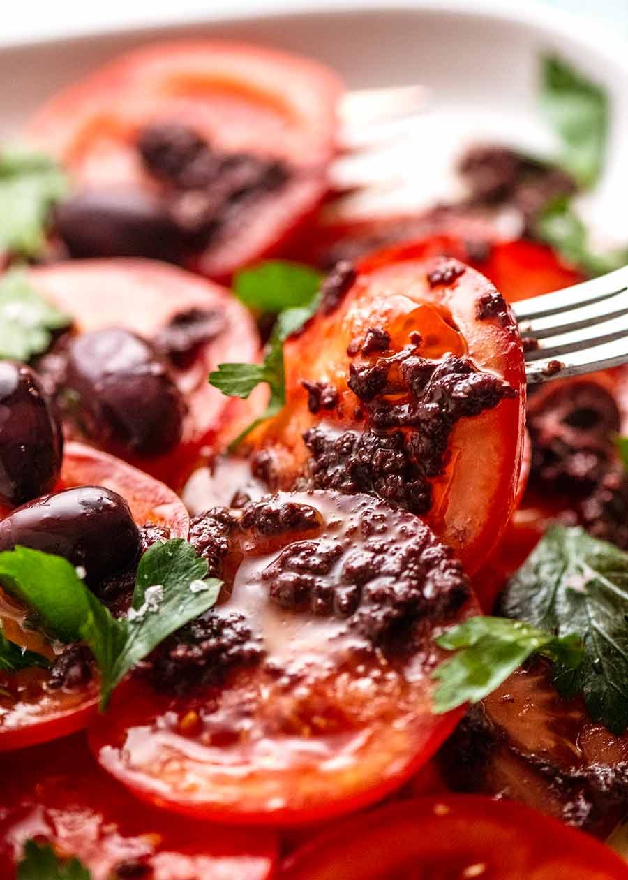 Fork picking up piece of Tomato Salad with Olive Tapenade
