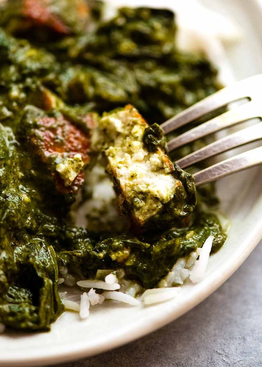Close up of a piece of Paneer in Palak Paneer, showing creamy soft inside