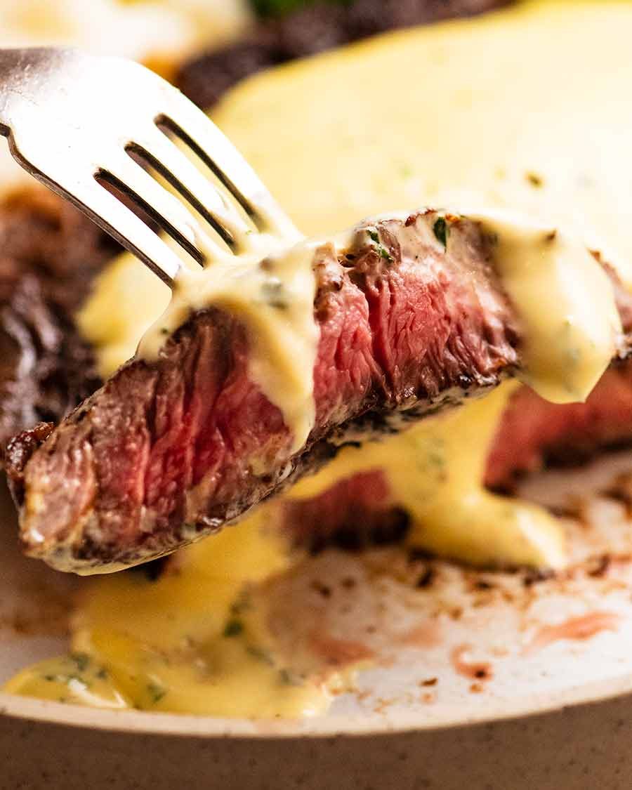 Close up of fork picking up a slice of steak with Bearnaise Sauce
