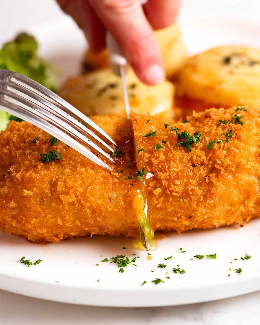 Cutting a piece of Chicken Kiev stuffed with garlic butter