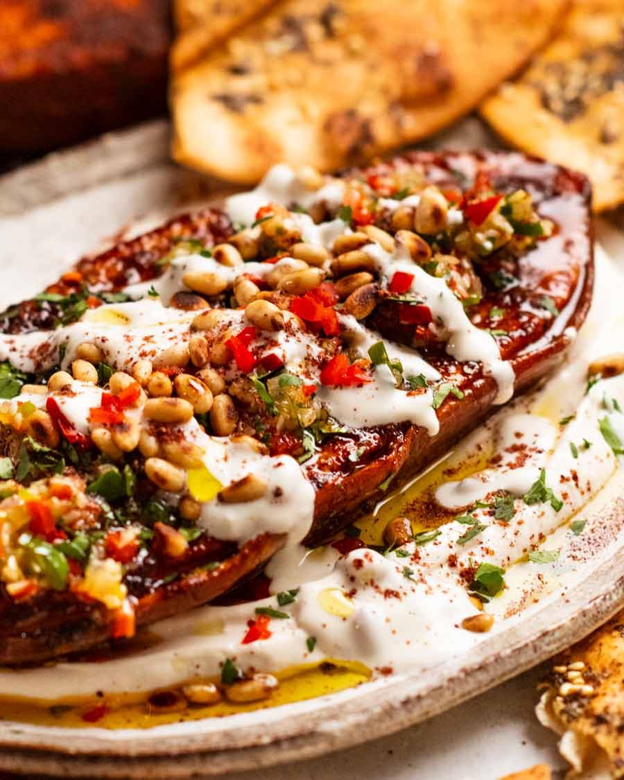 Roasted sweet potato steaks on a plate with whipped tahini yogurt sauce